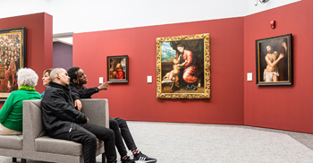 people sitting enjoying paintings in an art gallery